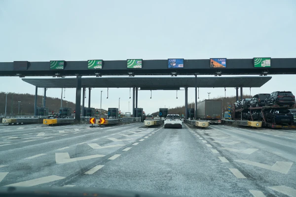 Approaching the Øresund Bridge toll booths with Bizz automatic, card and cash payment lanes, with a car transporter truck on the right